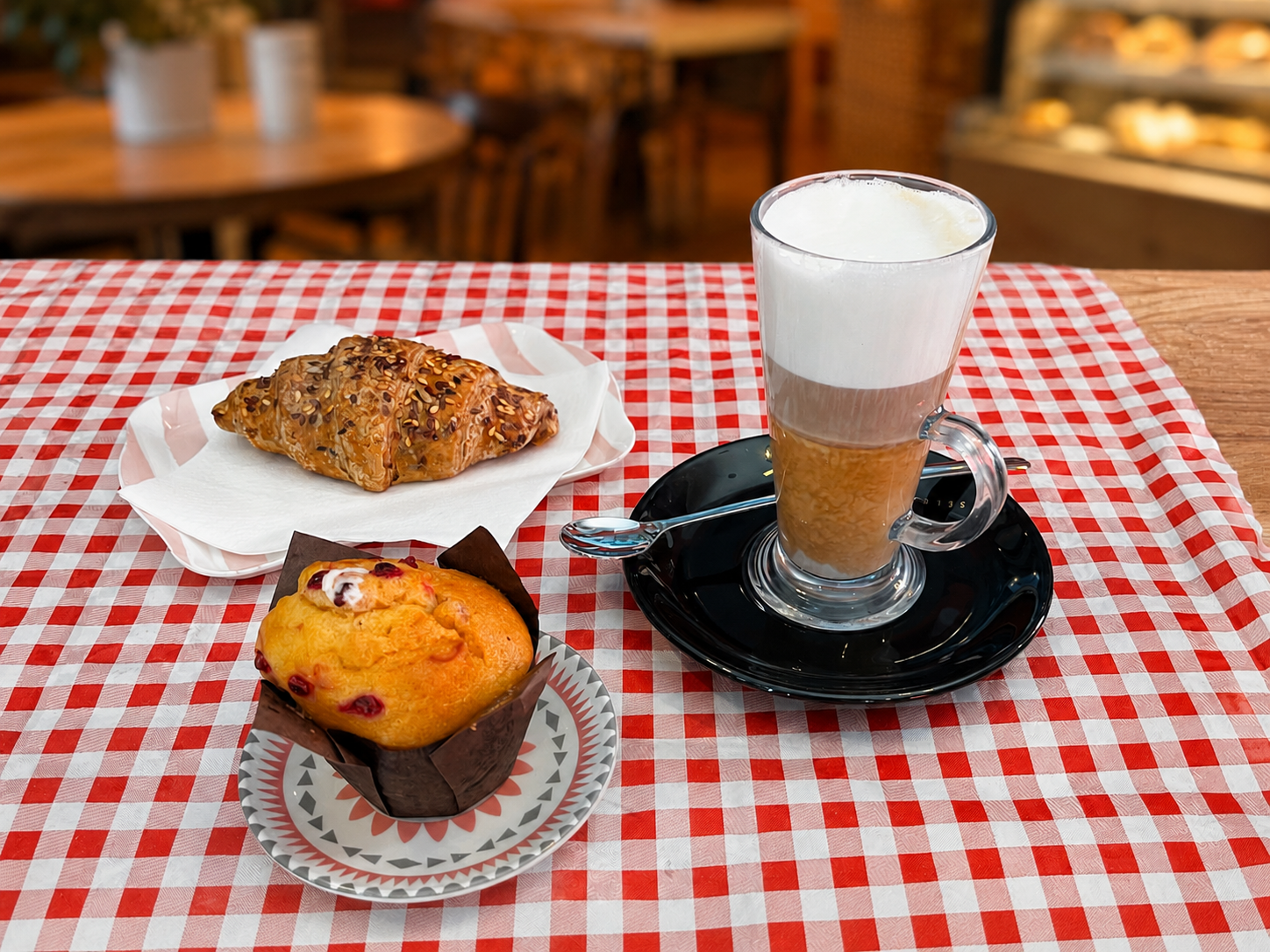 Croissant, muffin and a latte on a red checkered cloth at Origini Salumeria in Swieqi